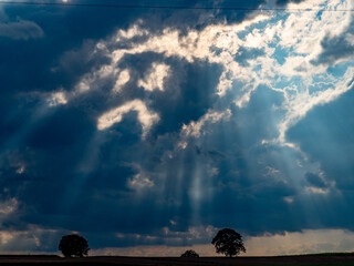 Sonne bricht durch dunklen Wolkenhimmel