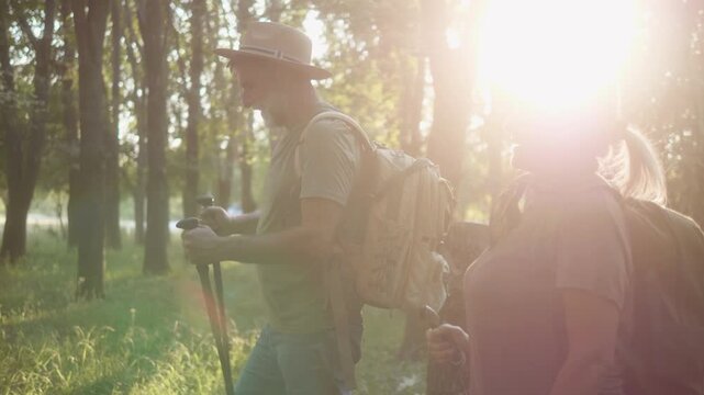 Side view of a elderly couple with a backpacks and trekking poles hiking  in forest