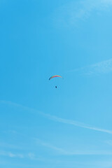 Paraglider in the air fly in blue clear summer sky.