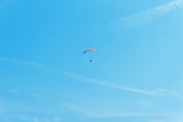 Paraglider in the air fly in blue clear summer sky.