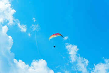 Paraglider in the air fly in blue clear summer sky.