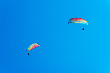 Paraglider in the air fly in blue clear summer sky.