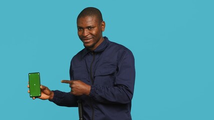 Portrait of happy security guard at work showcasing green screen laptop while overseeing premises....