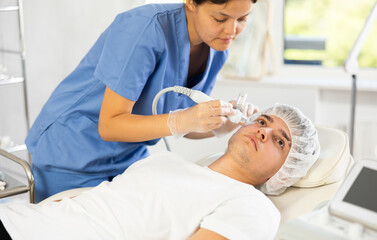 Female cosmetic doctor expertly administers procedure to male patient using hydrogen oxygen...