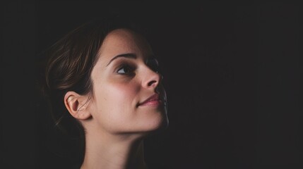 Fototapeta premium Serene Beauty - Artistic Portrait of Woman with Natural Makeup Illuminated by Soft Light in Dark Studio
