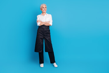 Full length photo of pensioner lady crossed hands look empty space serve clients dressed waitress uniform isolated on blue color background