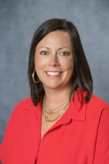 Headshot of Caucasian brunette middle age business woman in studio on gray backdrop