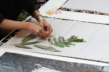 A person carefully arranging leaves on fabric for eco printing, showcasing the art of natural...