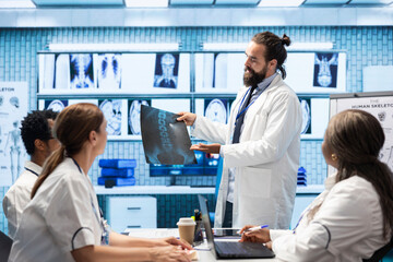 Obraz premium General practitioner gathering healthcare experts review x ray scans in a private clinic meeting. Licensed professionals focusing on diagnostics and disease prevention, collaborative teamwork.