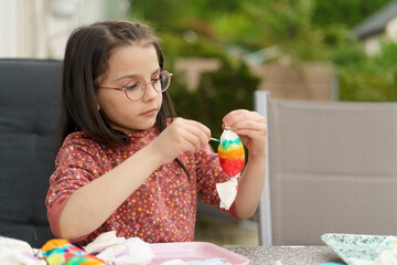 Little girl with glasses making crafts sitting at the table in the backyard of her house. Concept...