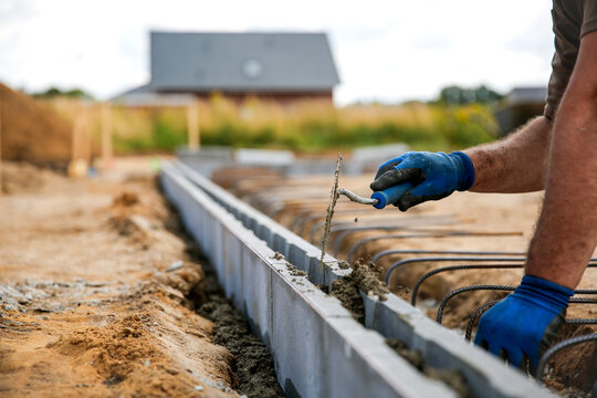 Close up of a bricklayer worker making cement mortar on a wall block 