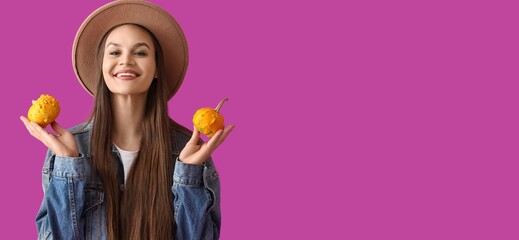 Pretty young woman holding pumpkins on magenta background with space for text