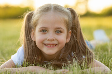 Happy little girl lying on grass and smiling. Perfect for innocence and joy of childhood concept....