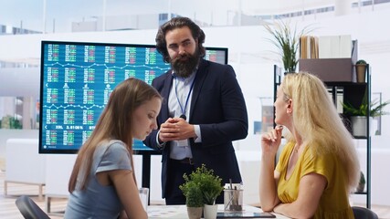 Financial adviser presents market analytics to clients using large screen, emphasizing data driven decision making. Broker showing statistical charts about stock exchange indicators, camera B