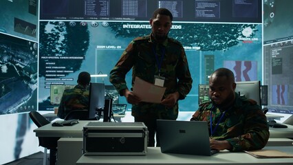 Intelligence agents in modern operations center managing surveillance activity and synchronizing...