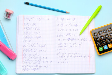Copybook with maths formulas, calculator and stationery on blue background