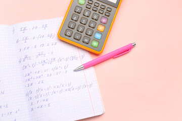Copybook with maths formulas, pen and calculator on pink background