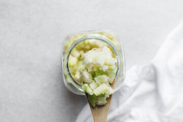 Overhead view of apple cheong in a glass jar on a white background, top view of korean apple cheong in a transparent jar, apple in sugar syrup, process of making apple cheong