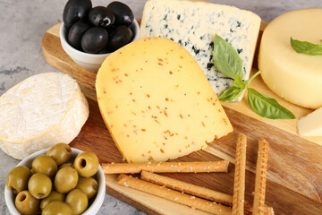 Wooden board with different types of cheese on table, closeup