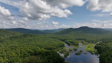 Obraz premium Beautiful green mountain range with gentle creeks in valley under blue sky with clouds in summer Adirondack Mountains New York State West Canada Creek Historic Confluence