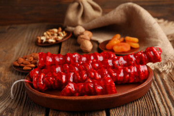 Plate with tasty churchkhela on wooden background