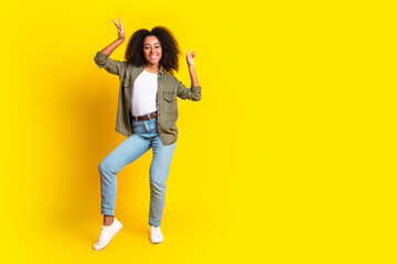 Full size photo of carefree nice girl dressed khaki jacket jeans pants dancing near empty space isolated on yellow color background