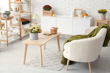 Interior of stylish living room with white sofa and chrysanthemum flowers on coffee table