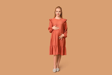 Beautiful happy pregnant woman on brown background