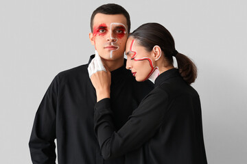 Young couple with painted faces on light background
