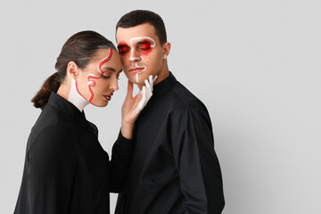 Young couple with painted faces on light background