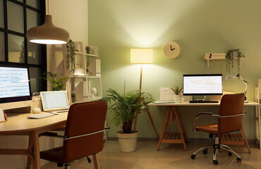 Stylish workplaces of programmer with modern computers and glowing lamps in office