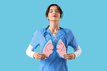 Female doctor with paper lungs on blue background