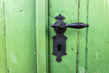 Ancient metal handle with a lock on a wooden door