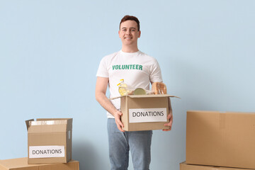 Male volunteer with donation boxes near blue wall