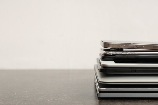 Stack of modern gadgets on table against light background