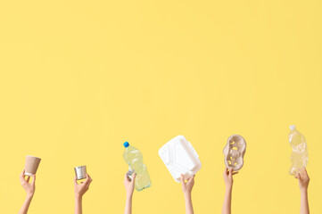 Female hands holding different litter on yellow background. Recycling concept