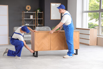 Loaders covering chest of drawers with polyethylene film in room