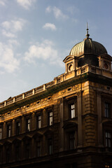 Golden sunlight illuminates ornate historic building with domed roof in Krakow, Poland
