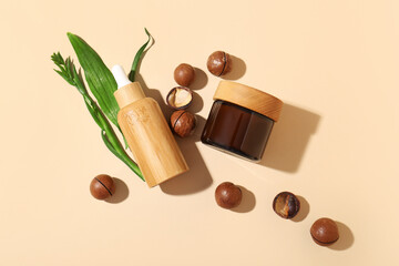 Macadamia nuts, green leaves, jar and bottle of cosmetic product on beige background