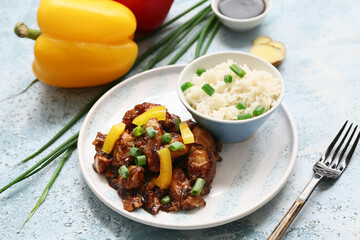 Tasty sweet and sour chicken with rice in plate, pepper and fork on blue grunge background, closeup