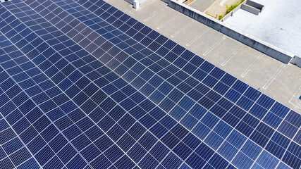 Close-up of an extensive array of blue solar panels installed on tilt frames and mounted at an angle highlighting the efficiency and organization of solar energy capture on a flat roof.