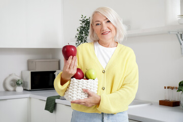 Mature woman with basket of apples in kitchen