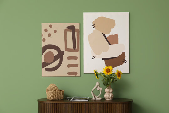 Statuette, wicker baskets and vase with beautiful sunflowers on chest of drawers in living room