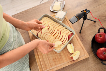 Female blogger cooking apple pie while recording video class in kitchen, closeup
