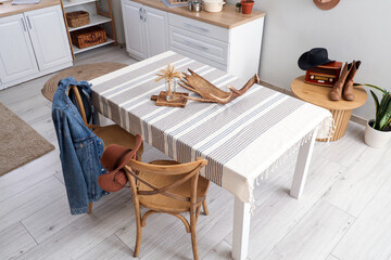 Interior of kitchen with dining table, cowboy hat and denim jacket on chairs