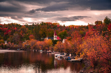 Autumn in picturesque village of Wakefield, boats on the Gatineau River, red church steeple,...