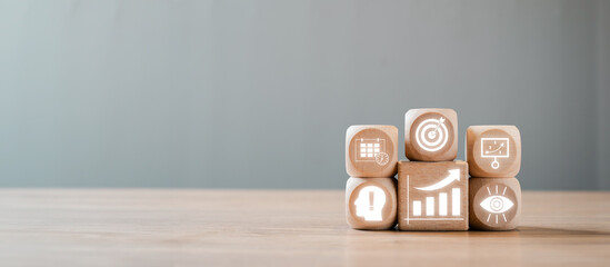 Wooden blocks with icons illustrating performance management concepts such as business goals, analytics, and strategy on a wooden table.