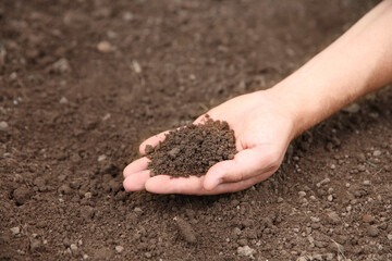 Woman holding pile of soil outdoors, closeup. Space for text