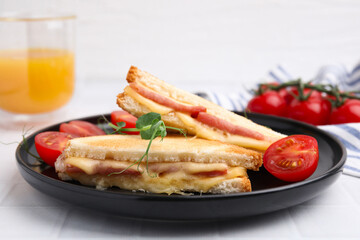 Pieces of toasted bread with melted cheese, ham and tomatoes on white table