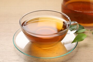 Refreshing green tea in cup and leaves on wooden table, closeup